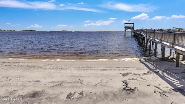 view of dock featuring a beach view and a water view