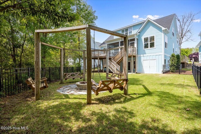 rear view of house featuring a lawn, a fire pit, a fenced backyard, a wooden deck, and stairs