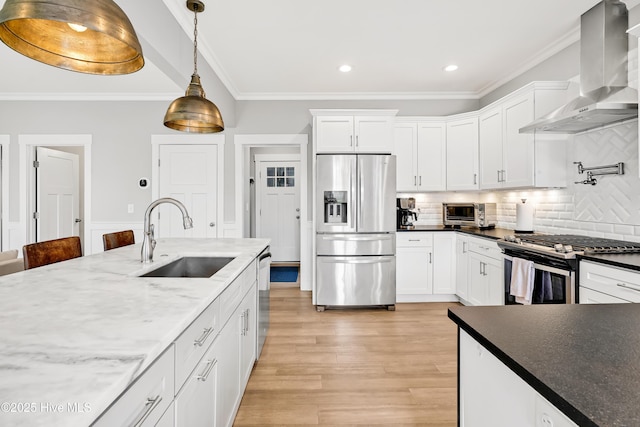 kitchen featuring a sink, appliances with stainless steel finishes, wall chimney exhaust hood, crown molding, and hanging light fixtures