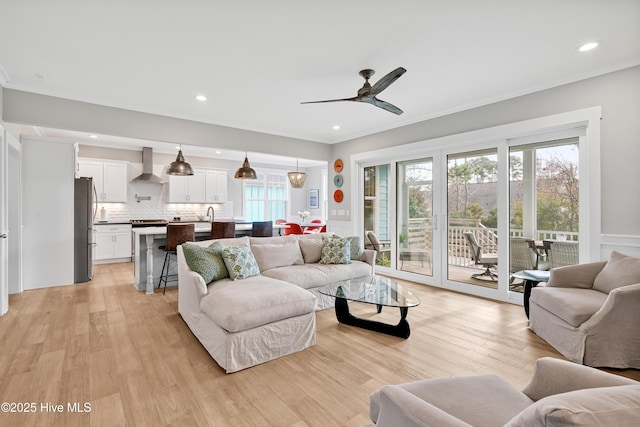 living area featuring recessed lighting, a wainscoted wall, ornamental molding, light wood-style floors, and ceiling fan