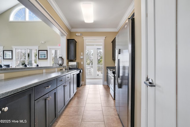 kitchen featuring stainless steel appliances, dark countertops, ornamental molding, and light tile patterned flooring