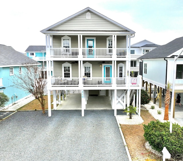 raised beach house featuring a carport, a balcony, and ceiling fan