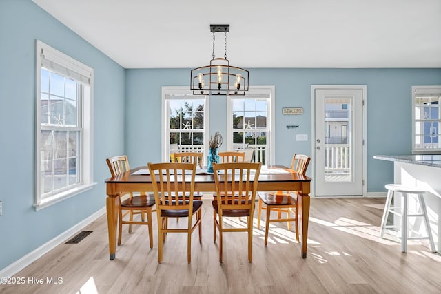 dining room with light hardwood / wood-style flooring, plenty of natural light, and an inviting chandelier