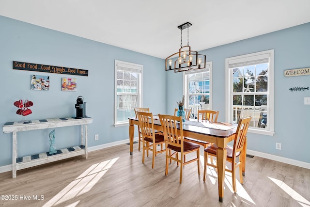 dining space with light hardwood / wood-style floors and a notable chandelier