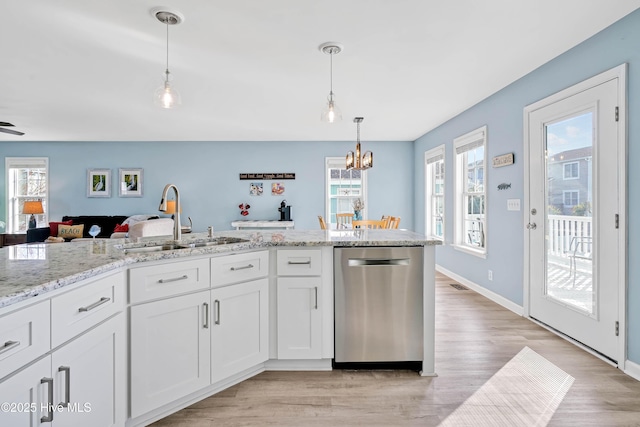 kitchen with white cabinetry, sink, hanging light fixtures, stainless steel dishwasher, and light stone counters