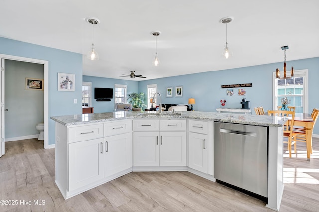 kitchen featuring sink, hanging light fixtures, stainless steel dishwasher, an island with sink, and white cabinets