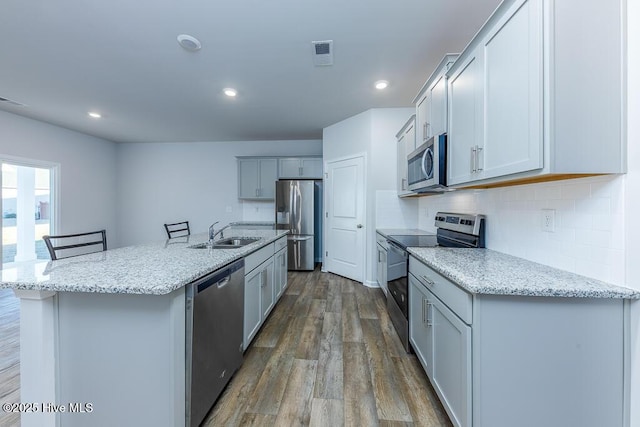 kitchen featuring appliances with stainless steel finishes, sink, a breakfast bar area, dark hardwood / wood-style flooring, and a center island with sink