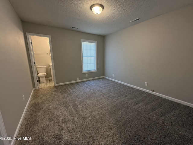 unfurnished bedroom featuring ensuite bathroom, carpet flooring, and a textured ceiling