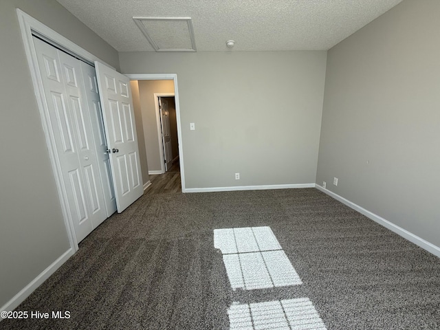 unfurnished bedroom featuring dark carpet, a closet, and a textured ceiling