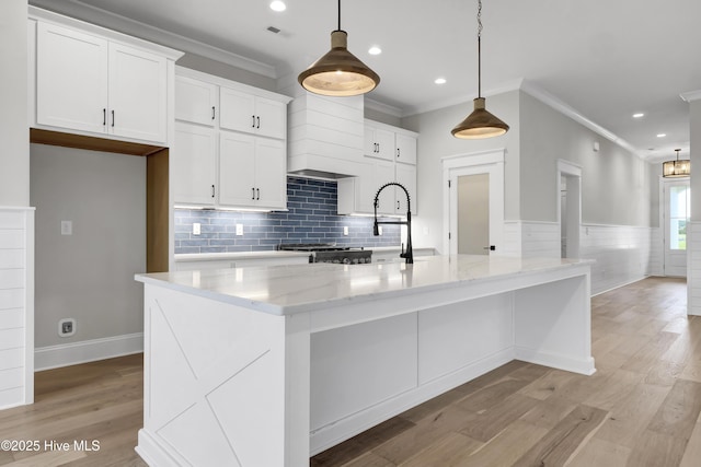 kitchen featuring light stone counters, decorative light fixtures, light hardwood / wood-style floors, and white cabinets