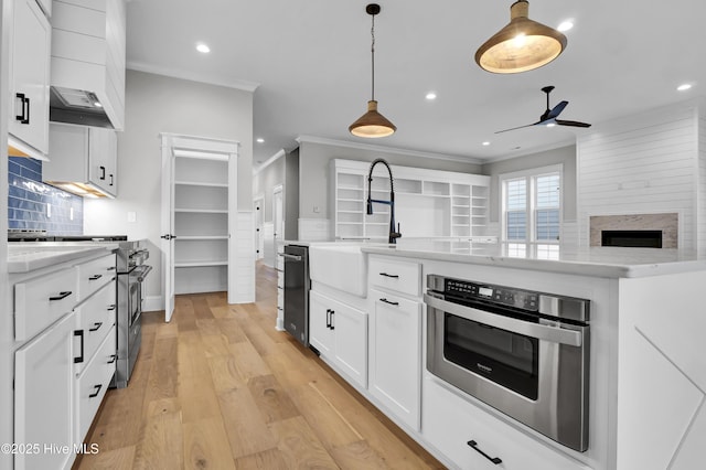 kitchen with high end range, decorative light fixtures, light hardwood / wood-style flooring, ornamental molding, and white cabinets