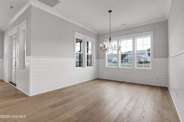 unfurnished dining area with crown molding, a notable chandelier, and light wood-type flooring