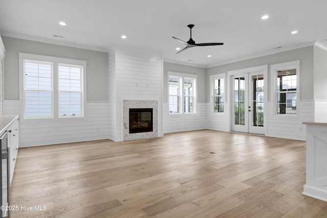 unfurnished living room featuring a high end fireplace, light hardwood / wood-style flooring, french doors, and ceiling fan