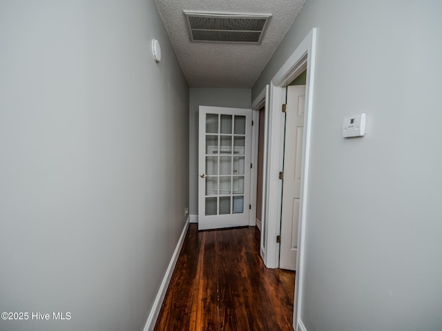 corridor with dark hardwood / wood-style floors and a textured ceiling