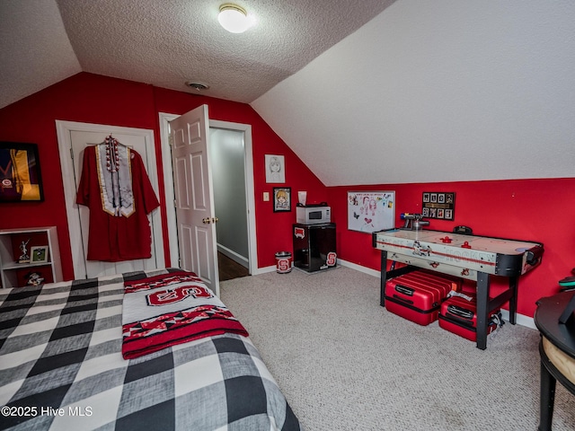 bedroom with carpet flooring, vaulted ceiling, and a textured ceiling