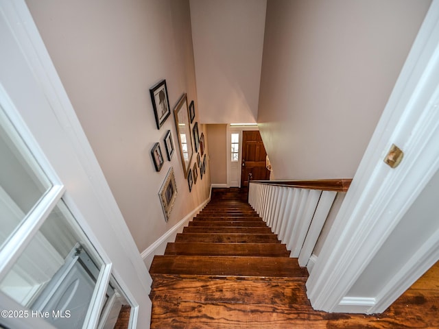 staircase featuring hardwood / wood-style flooring and a towering ceiling