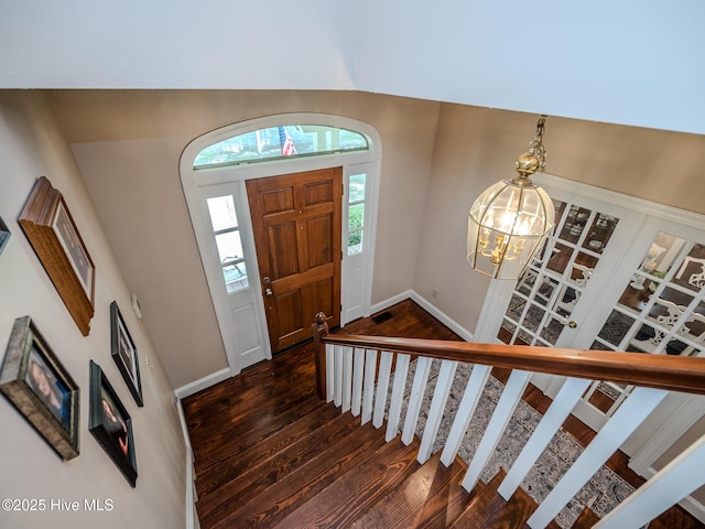 entryway with an inviting chandelier and dark wood-type flooring