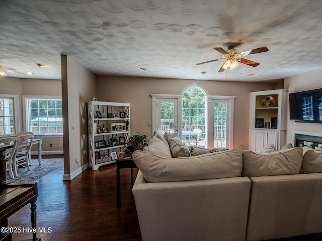 living room featuring dark hardwood / wood-style flooring, a textured ceiling, a wealth of natural light, and ceiling fan