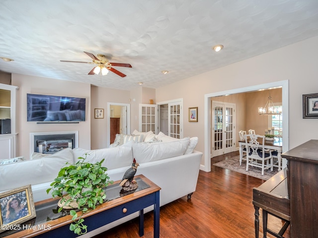 living room with dark hardwood / wood-style flooring, ceiling fan with notable chandelier, and a textured ceiling