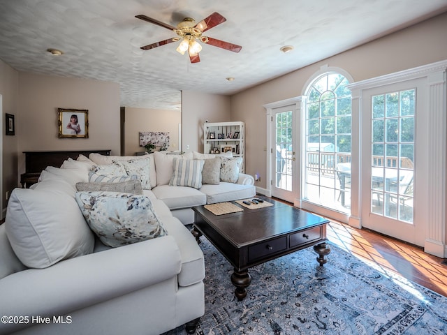 living room with hardwood / wood-style flooring, ceiling fan, and a textured ceiling