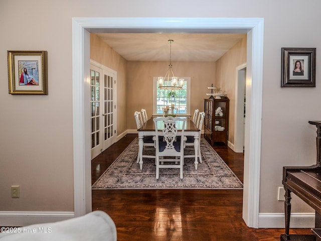 dining area with dark hardwood / wood-style floors, an inviting chandelier, and french doors