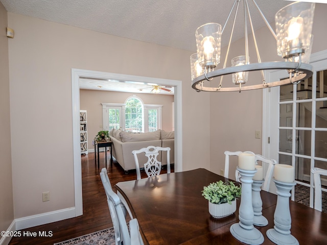 dining space with ceiling fan with notable chandelier, dark wood-type flooring, and a textured ceiling