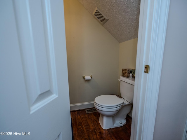 bathroom featuring lofted ceiling, toilet, hardwood / wood-style floors, and a textured ceiling