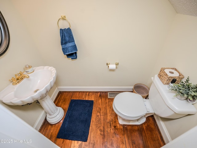 bathroom featuring wood-type flooring, toilet, and a textured ceiling