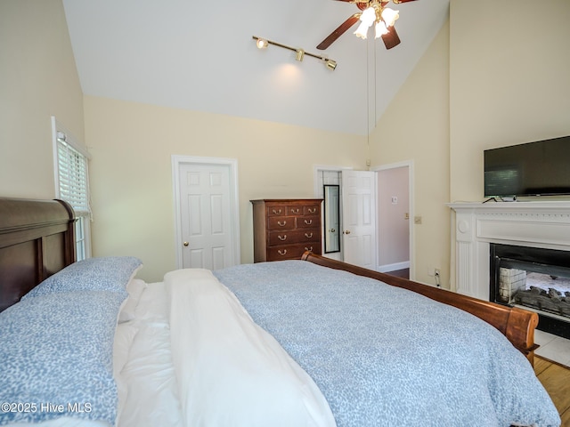 bedroom featuring a multi sided fireplace and high vaulted ceiling