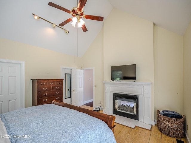 bedroom featuring ceiling fan, high vaulted ceiling, and light wood-type flooring