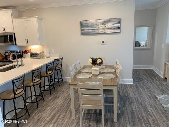 dining area featuring sink, crown molding, and dark hardwood / wood-style floors