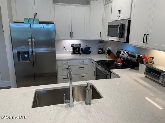 kitchen featuring light stone countertops, appliances with stainless steel finishes, sink, and white cabinets