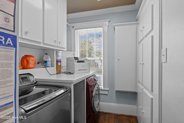 washroom featuring cabinets, crown molding, washing machine and clothes dryer, and dark hardwood / wood-style flooring