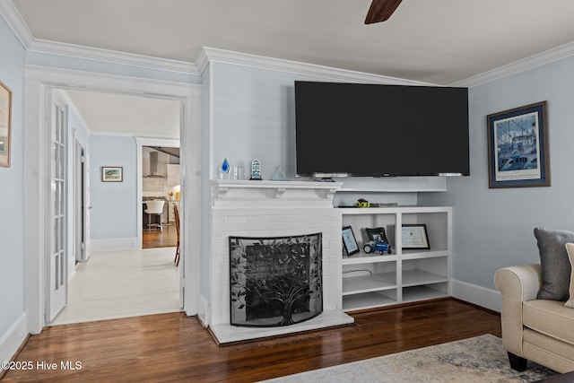 living room featuring crown molding, a brick fireplace, hardwood / wood-style flooring, and ceiling fan