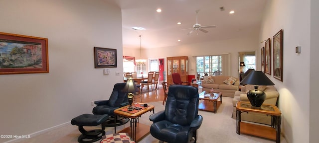 living room with ceiling fan, light colored carpet, and a high ceiling