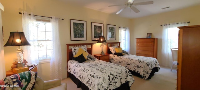 bedroom featuring ceiling fan, light carpet, and multiple windows