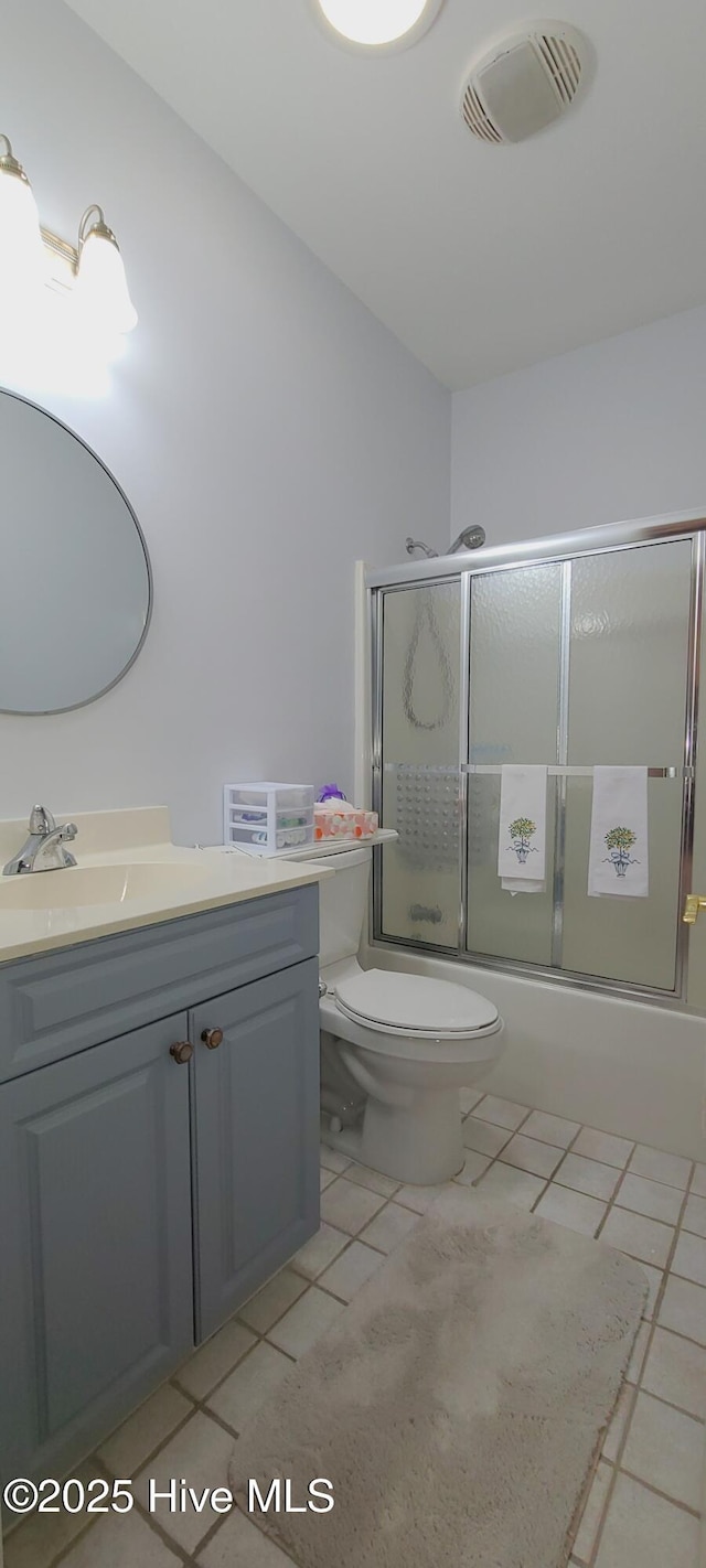 full bathroom featuring vanity, bath / shower combo with glass door, tile patterned floors, and toilet