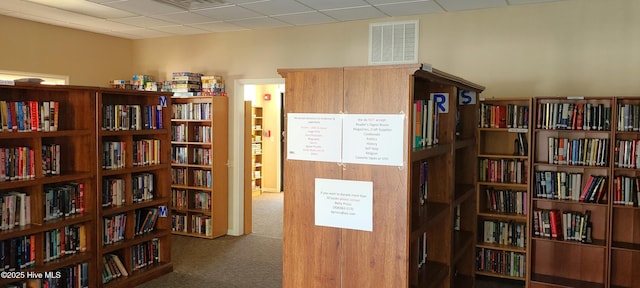 hallway with a paneled ceiling and carpet