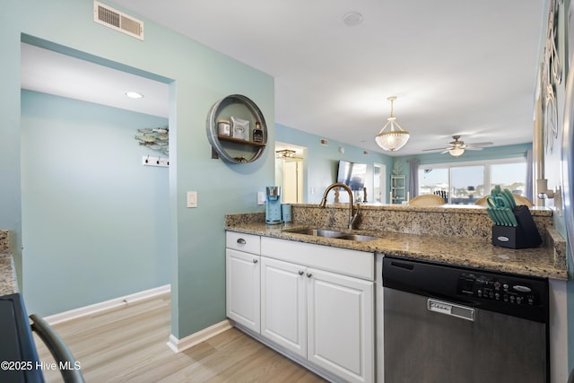 kitchen featuring sink, light hardwood / wood-style flooring, white cabinets, stainless steel dishwasher, and dark stone counters