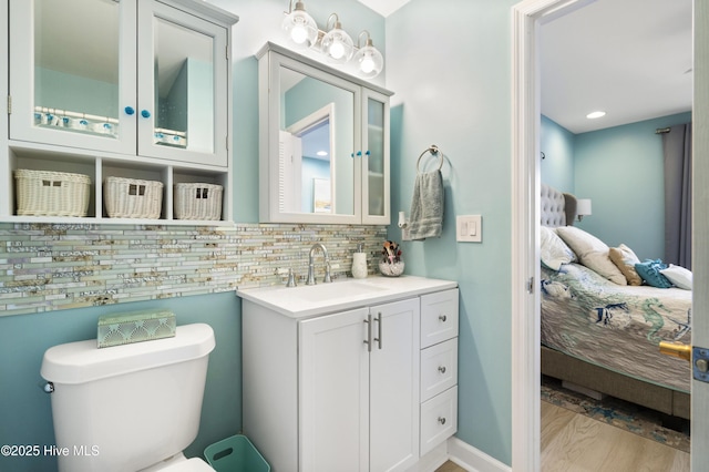 bathroom featuring vanity, hardwood / wood-style floors, backsplash, and toilet