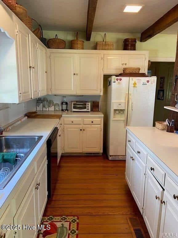 kitchen with dark hardwood / wood-style flooring, white refrigerator with ice dispenser, white cabinets, and beam ceiling