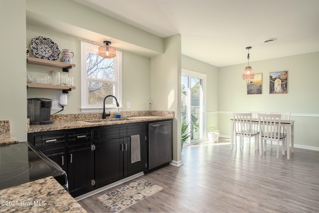 kitchen featuring sink, hanging light fixtures, stainless steel dishwasher, light stone countertops, and light hardwood / wood-style floors