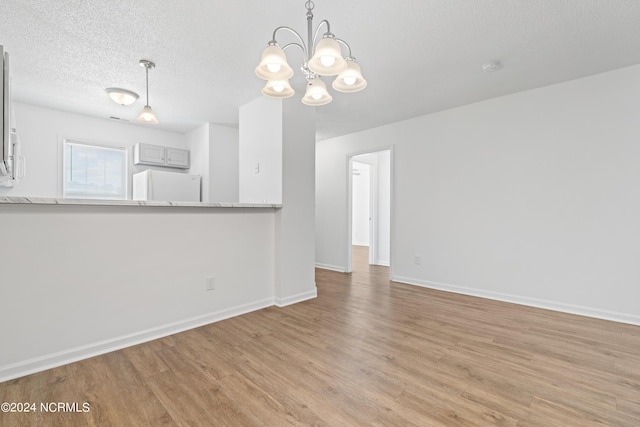 unfurnished living room featuring a textured ceiling and light hardwood / wood-style flooring