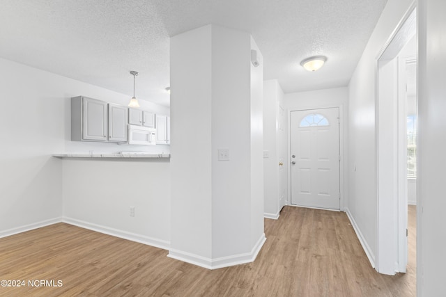 foyer with a textured ceiling and light wood-type flooring