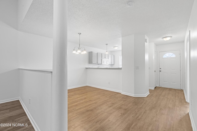 interior space featuring an inviting chandelier, light hardwood / wood-style flooring, and a textured ceiling