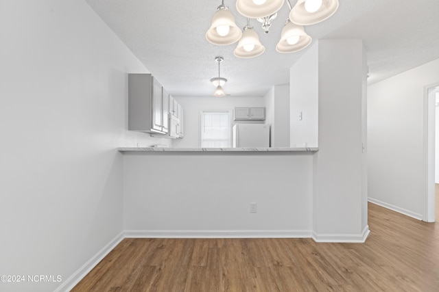 kitchen featuring white appliances, wood-type flooring, gray cabinets, and kitchen peninsula