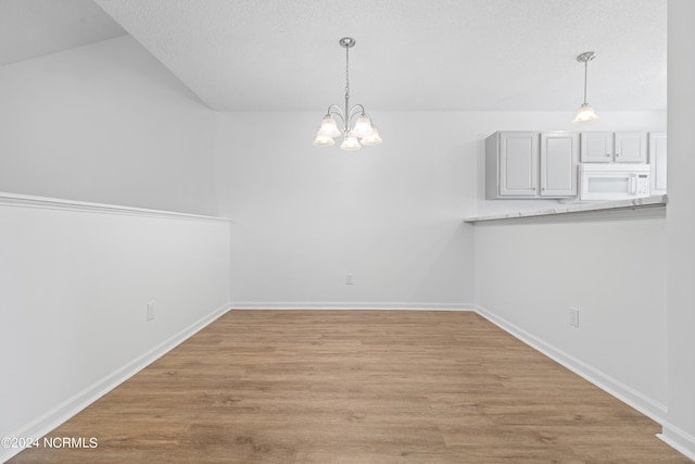 unfurnished dining area featuring a notable chandelier and light hardwood / wood-style floors