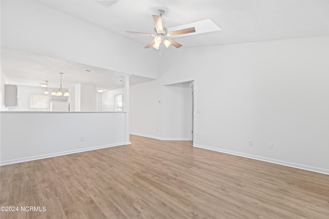 unfurnished room featuring vaulted ceiling, light hardwood / wood-style floors, ceiling fan with notable chandelier, and decorative columns