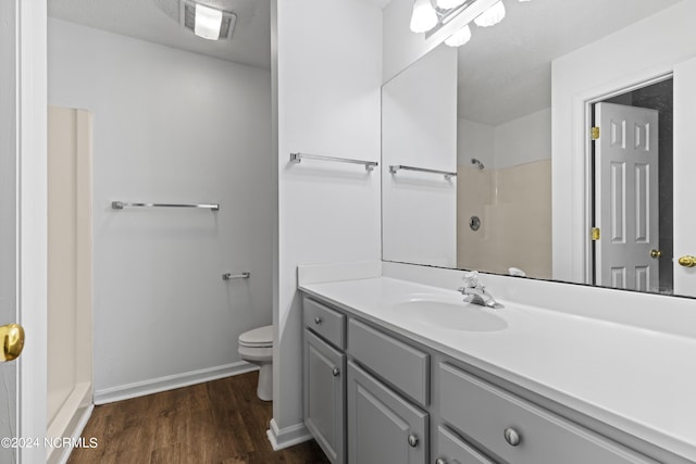 bathroom with vanity, hardwood / wood-style floors, a shower, and toilet