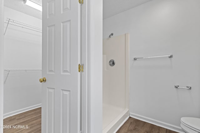 bathroom featuring walk in shower, toilet, hardwood / wood-style floors, and a textured ceiling